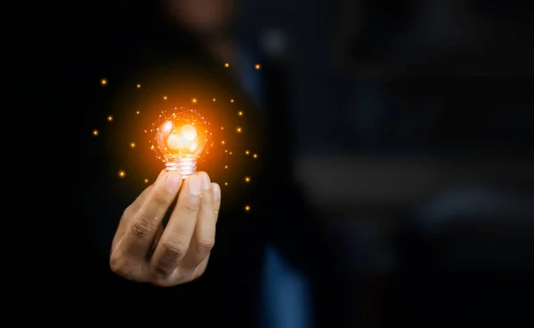 Light bulb in hand of businessman wearing suit in black background. Ideas for Success and new idea or inspiration with Innovation , technology based on data from the Internet, big data.