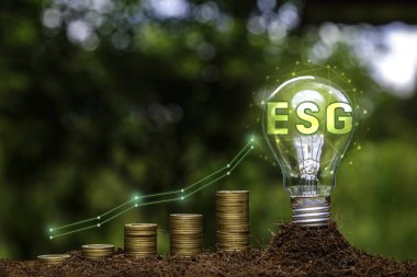 Ampulde ESG simgesi ve yeşil doğa arka planında Altın Sikke grafiği. Çevreye, topluma, yönetime veya sanayiye ESG yatırımı. Esg Yatırım, yeşil enerji yenilenebilir konsept