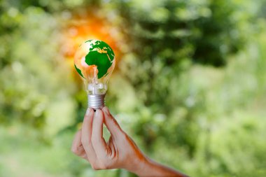 Yenilenebilir enerji sürdürülebilir. Doğada yeşil çimen arka planında yeşil bir dünya. Yenilenebilir enerji kaynakları için ampul. Fikir yeniliği ilhamı. Ağ Sıfır Yayılımı Çevre Koruma.