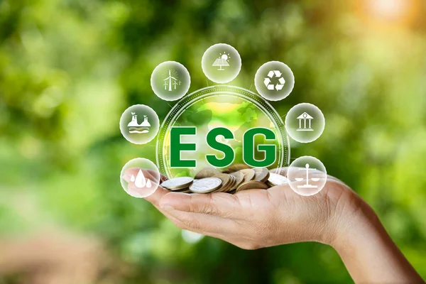 green energy concept. esg icon on pile of gold coins in hand on green nature background. Investing in the environment, society, governance, invest ESG in the industrial. ecology energy renewable.