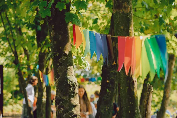 Yaz parkında ağaçların arasında renkli bayraklar. Kutlama konsepti. Açık havada kağıt festivali dekorasyonu..