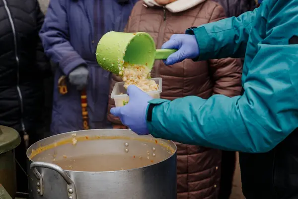Bir adam fakirleri doyurmak için tencereden yulaf lapası döker.