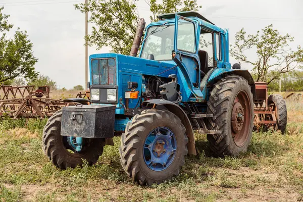 Güneşli yaz gününde tarımsal alanda karavanlı mavi traktör.