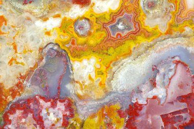A cross section of the agate stone with quartz geode. Multicolored silica bands colored with metal oxides are visible. Macro photography of the surface of the cut. Origin: Atlas mountains, Morocco.