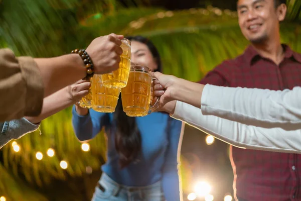 Group of happy friends drinking and toasting beer at a party backyard