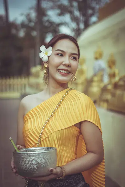 A beautiful Thai woman wearing a Thai traditional dress playing Songkran festival in the temple