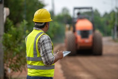 İnşaat mühendisi asfalt yol yapmak için yol silindirini inceliyor