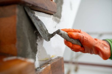 Bir insan duvara çimento sürmek için bir mala kullanıyor. El emeği ve sıkı çalışma kavramı, kişinin fiziksel olarak emek gerektiren bir işle meşgul olması gibi..