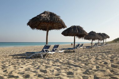 Romantik plaj tatili, aşk çifti manzarası şemsiye altında sandalyeler, panoramik ada cenneti tatili. Renkli deniz göğü, yakın plan