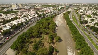 Yüksek açılı bir çekim güzel bir şehir nehrini, yeşil alanı ve Meksika, Monterrey 'de güneş ışığı altında hareketli bir şehri yakalar.