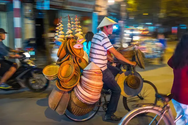 Korb Und Hutverkäufer Auf Dem Fahrrad Einer Belebten Straße Hanoi lizenzfreie Stockfotos