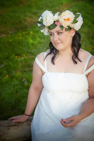 Slavic plump plump chubby girl in long white dress on the feast of Ivan Kupala with flowers on nature on summer evening