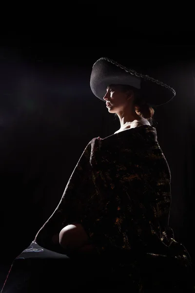 The silhouette of a girl in a veil looking like a statue or sculpture on black background. A model poses for a photo shoot in the studio