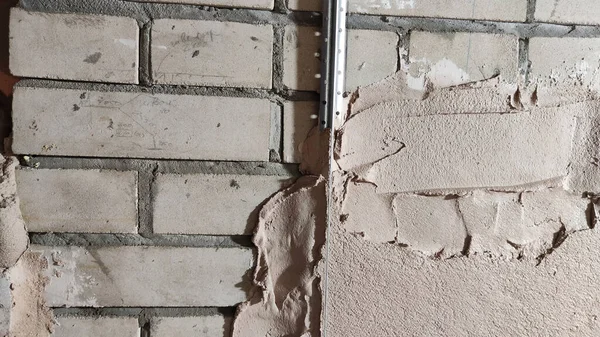 Plastering cement at wall for renovation house. Putty grey brick wall background. Partly plastered new brick wall with wet plaster for abstract background and texture