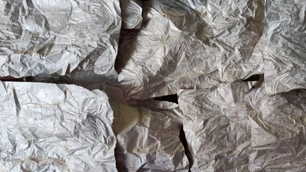 Pieces of crumpled silver foil sheets. Close up. Abstract background and texture