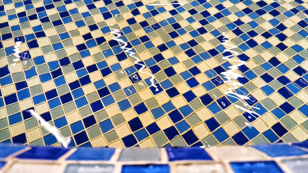 Swimming pool blue mosaic tile texture and background with clear water