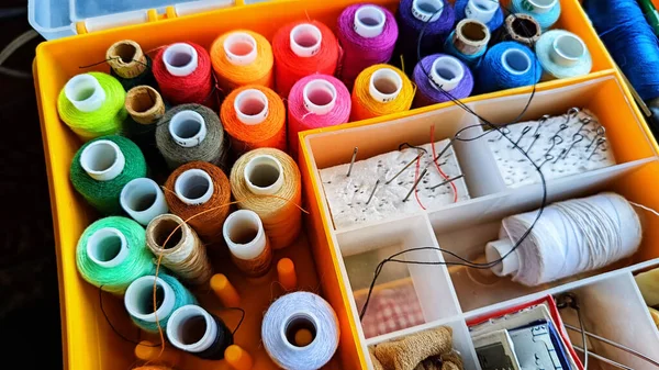 Storage box with spools of multi-colored threads, sewing needles. Storage system for sewing needlework at home and office