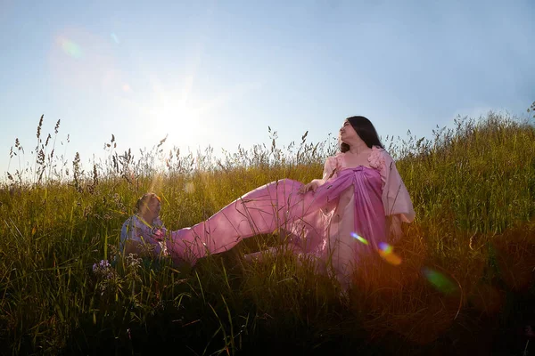 Young plump curvy beautiful teenage girl in a field or meadow on sunny summer day in the evening sunset sun. Plump black-haired and black-eyed oriental model from the east fairy tale