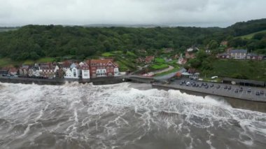 Kuzey Yorkshire, İngiltere 'deki Sandsend' de dalgaların sahil şeridine çarptığı 4K hava görüntüsü.