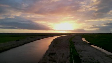 İngiltere, Suffolk, Herringfleet 'de Waveney Nehri üzerinde muhteşem bir günbatımının 4k insansız hava aracı görüntüleri.