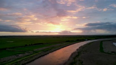 İngiltere, Suffolk, Herringfleet 'de Waveney Nehri üzerinde muhteşem bir günbatımının 4k insansız hava aracı görüntüleri.