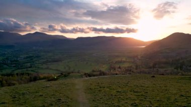 Cumbria, İngiltere 'de Keswick' e tepeden bakan güneşin doğuşunun 4k görüntüsü.