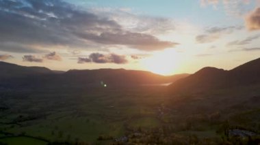 Cumbria, İngiltere 'de Keswick' e bakan tepelerin ardında güneşin batış zamanı 4K.