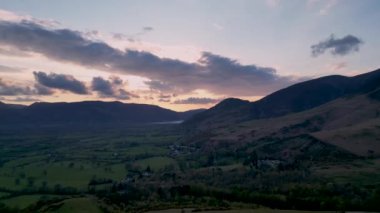 Cumbria, İngiltere 'de Keswick' e tepeden bakan güneşin doğuşunun 4k görüntüsü.