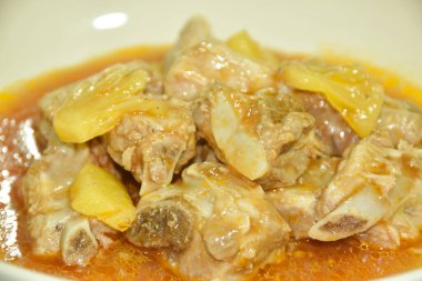 Kaynamış domuz kemiği, dilimlenmiş ananas ve domates yahnisi. 