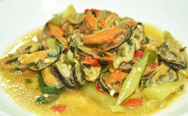 Baharatlı kızarmış midye dilimlenmiş soğan ve tabakta fesleğen yaprağı.