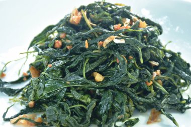 Soya soslu kızarmış jüt yaprakları tabakta çıtır sarımsak.