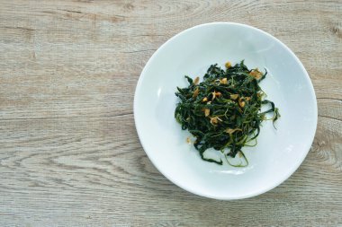 Soya soslu kızarmış jüt yaprakları tabakta çıtır sarımsak.