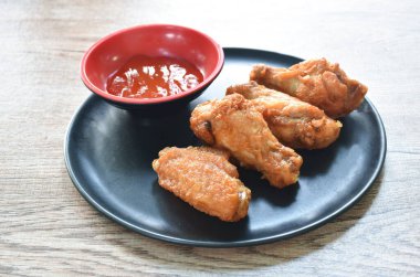 Kızarmış tavuk budu ve kanatlı biber sosu tabakta.