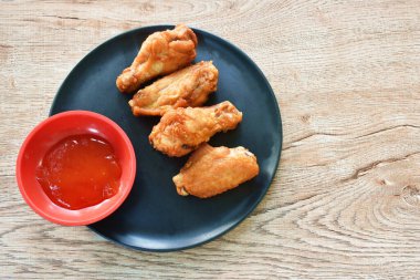 Kızarmış tavuk budu ve kanatlı biber sosu tabakta.