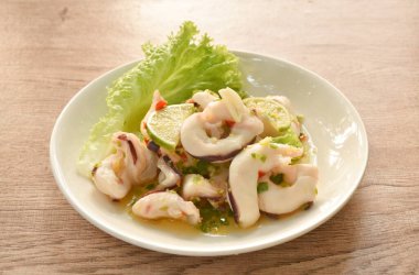 Thai spicy and sour steamed slice squid with lemon salad on plate  
