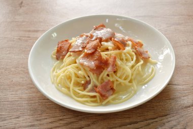 Kızarmış domuz pastırmasının üzerine beyaz soslu spagetti. 