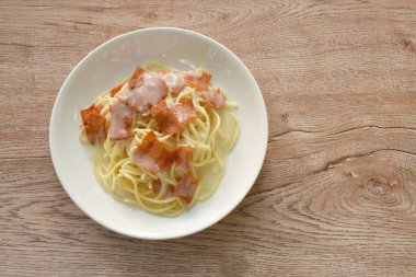 Kızarmış domuz pastırmasının üzerine beyaz soslu spagetti. 