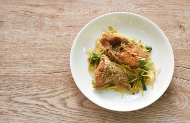 deep fried bass fish slice dressing soy sauce and spring onion on plate