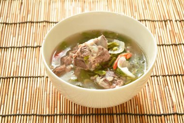 sıcak ve baharatlı domuz kemik demirhindi ve Tay otlar çorba kase üzerinde 