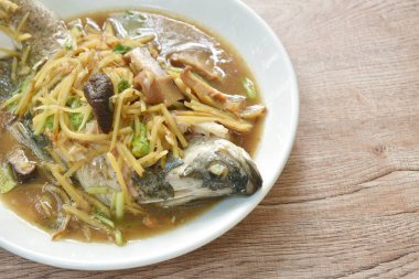 steamed bass fish dressing soybean gravy sauce topping slice ginger and mushroom on plate 