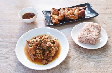 Baharatlı Tayland usulü kızarmış domuz salatası ızgara dilimlenmiş tavuk kanadı sosu tabakta.