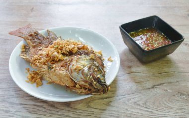 Kızarmış mango balığı tabakta baharatlı sebze sosu kabın içinde.