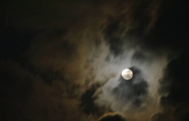 Gökyüzünde bulutların ardında yüzen parlak ay 