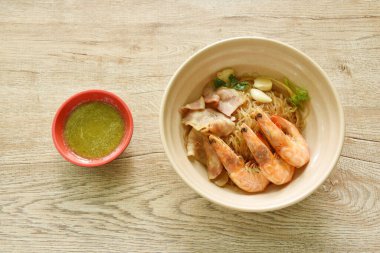 Baharatlı Tayland biber sosu soslu, cam erişteli karides ve domuz pastırması. 