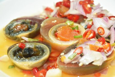 Haşlanmış siyah yumurta yarısı dilimlenmiş arpacık soğanı ve acı biberli salata.