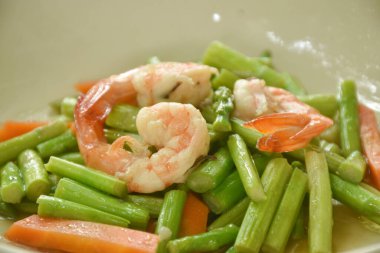 Kızarmış kuşkonmaz ve havuç ile istiridye soslu karides karıştırın. 