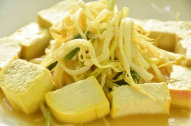 Kızarmış fasulye filizi, dilimlenmiş sarı tofu ve tabakta domuz pirzolası.