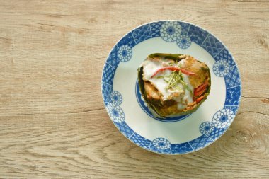 Hint cevizi sütü ve muz yaprağı tepsisinde limon yaprağı dilimi ile buharda pişirilmiş yılan başlı balık.