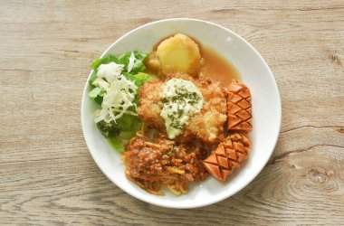 Kızarmış tavuk eti, patates püresi soslu peynir, spagetti ve lahana çünkü marul salatalı çift sosis tabakta. 