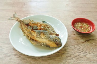 Kızarmış siyah kelebek ya da gümüş pomfret; tabağa yerleştirilmiş baharatlı acı biber sosu fincana batırılmış.